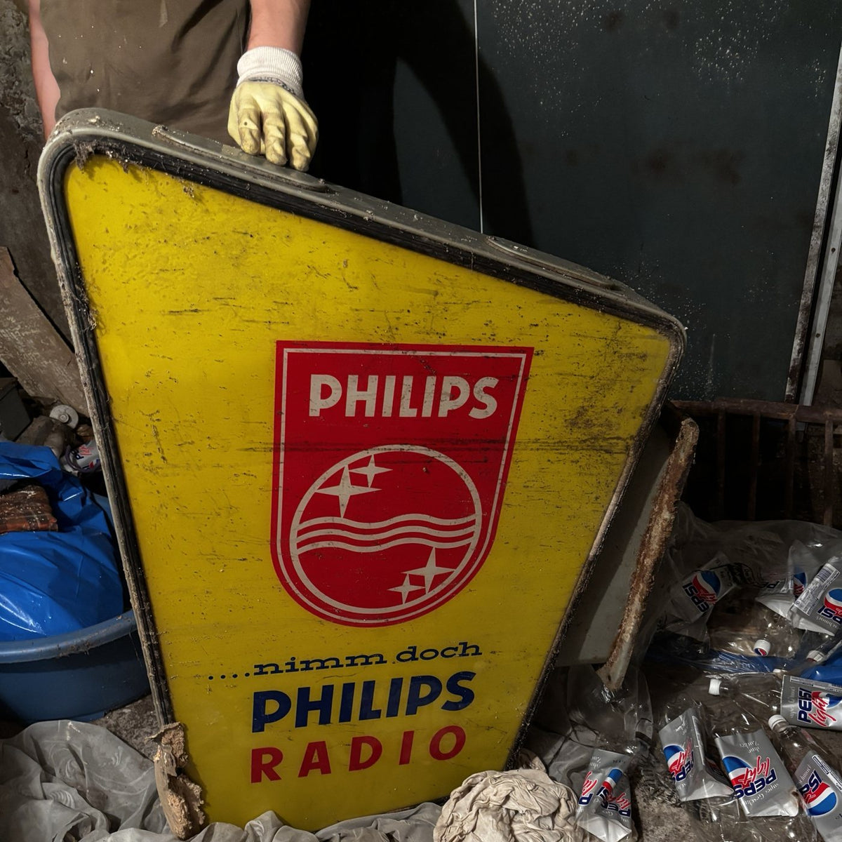 Alte Philips Radio Leuchtreklame wird bei einer Kellerräumung hochgehalten